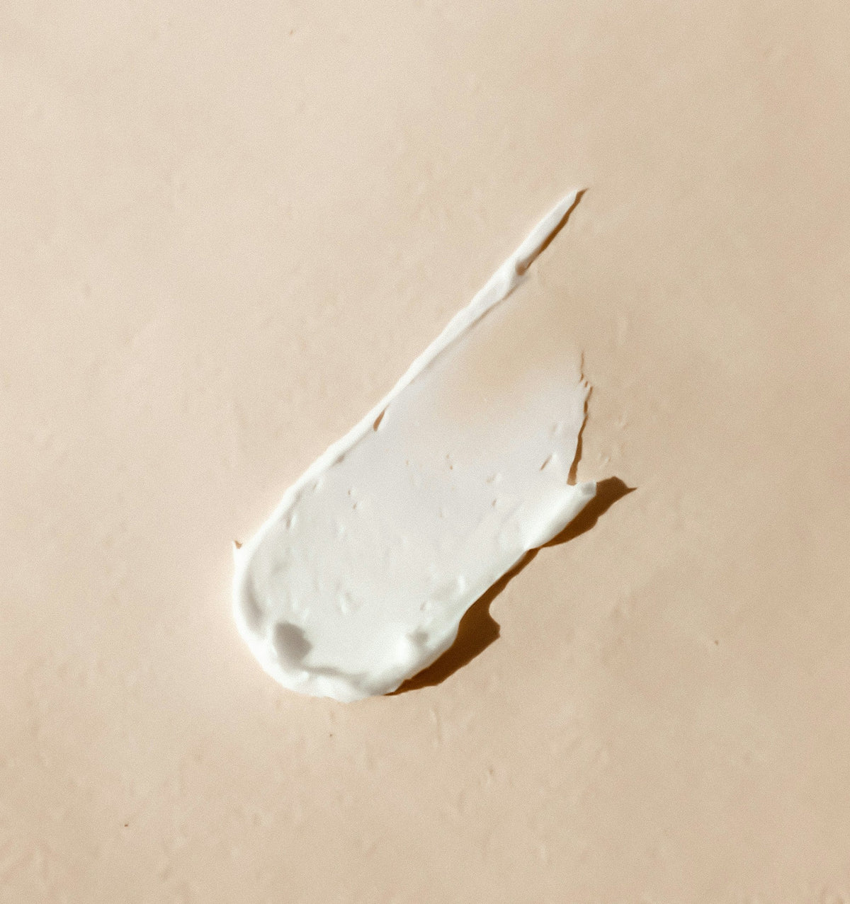 A swipe of rich moisturizing cream on a beige background
